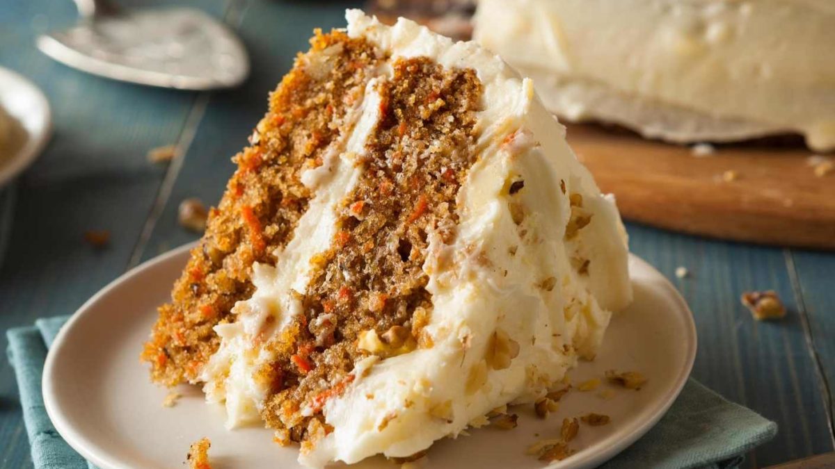 a slice of carrot cake laying on a side on a white plate